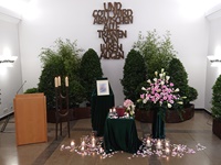 Feierhalle mit Dekorationsbäumen, Gesteck in rosa und weiß, Urnenschmuck, Rosenblütenblätter und Kerzen