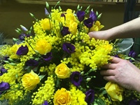 Fertigung eines Blumengesteckes mit gelben Rosen, Mimosen und violetten Lisianthus